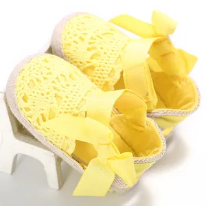 Vista detallada de zapatos de encaje amarillos para bebé con lazo y suela blanda