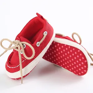 Dettaglio scarpe in tela per neonati con suola morbida rossa e pois rosa