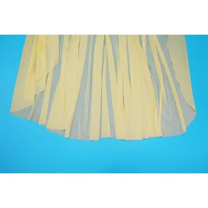 Close-up of the delicate pale yellow pleated mesh hem detail of a bodycon dress