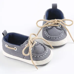 Dettaglio scarpe neonato in tela grigia con suole morbide e bordi intrecciati