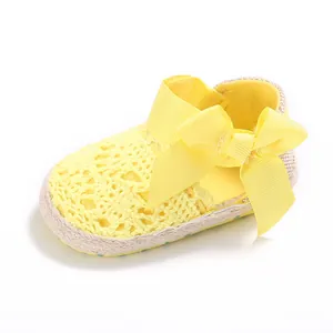 Yellow crochet baby walker shoes with a large decorative bow and soft flexible sole