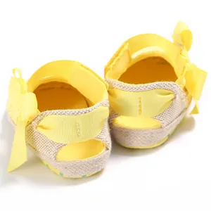 Vista trasera de zapatos amarillos para bebé con lazos y textura de lino para caminar