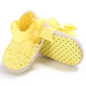 Vista detallada de zapatos de bebé amarillos de encaje calado con un lazo muy grande