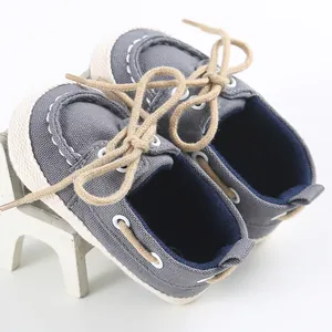Primo piano di scarpe in tela per neonati grigie con suole morbide e lacci marroni