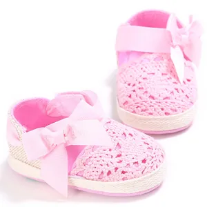 Primer plano de zapatos de bebé de ganchillo rosa con un gran lazo de cinta suave