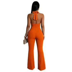 Detail van een sexy halter jumpsuit met open rug in fel oranje en uitlopende pijpen.