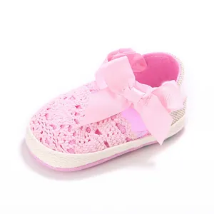 Primer plano de zapato de bebé de ganchillo rosa con suela blanda y lazo de satén