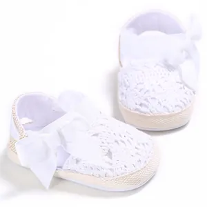Primer plano detallado de zapatos de bebé de ganchillo blanco con gran lazo suave