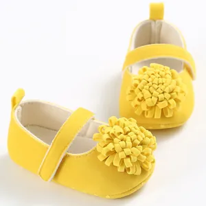 Primer plano de zapatos amarillos para bebé con decoración floral suave en la parte superior.