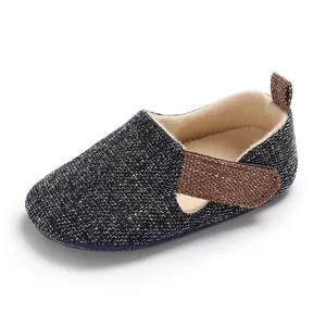 Primer plano de zapato para bebé en tela azul marino con correa marrón y forro beige