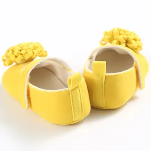 Vista detallada trasera de zapatos amarillos para bebés con suelas blandas y flores