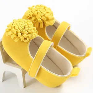 Primer plano de zapatos amarillos de bebé con flores y suela blanda para caminar