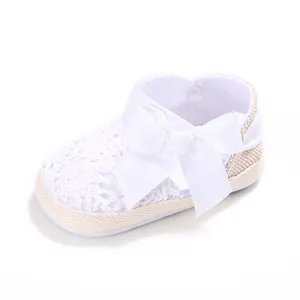 Primer plano de zapato de bebé de ganchillo blanco con un gran lazo de satén decorativo