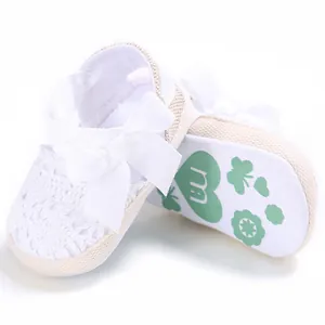 Close-up of white lace baby pre-walker shoes with ribbon bow and anti-slip sole