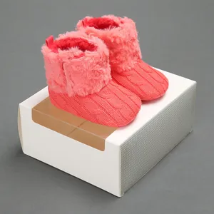 Stivaletti per neonati in maglia rosa corallo con fodera in peluche su confezione.
