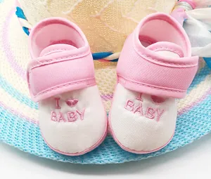 Primer plano de zapatos de bebé rosa y blanco con bordado I love baby