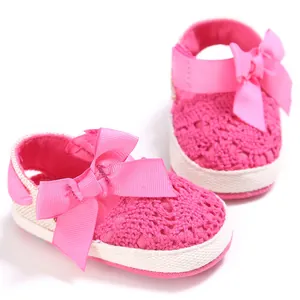 Vista detallada de zapatos de bebé calados de color rosa con un lazo de cinta