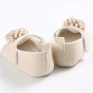 Detalle posterior de zapatos de bebé beige con suela blanda y flor en 3D