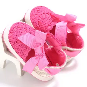 Détail en gros plan montrant la texture tricotée et le nœud rose des chaussures bébé