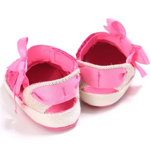 Close-up view of pink baby walking shoes with delicate ribbon bow details on heels.