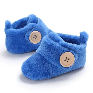 Detailed view of blue fuzzy winter baby booties featuring a wooden button and soft texture