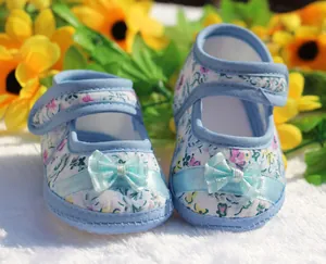 Vista detallada de zapatos de bebé azules con flores y una suela muy blanda y lazo
