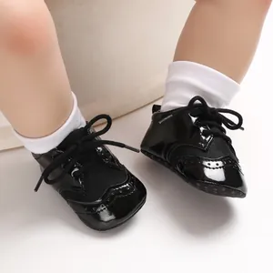 Detailed view of black patent leather baby shoes with lace-up closure and anti-slip soft sole