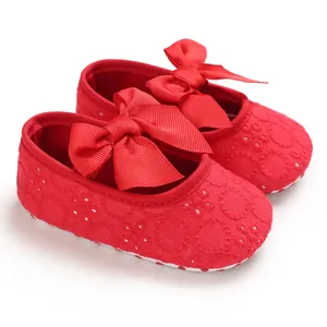 Détail des chaussures de marche bébé rouge avec broderie en dentelle et nœud en ruban