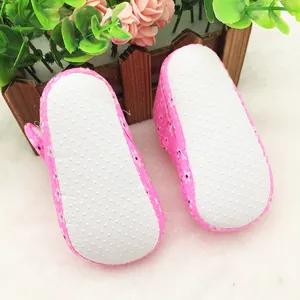 Detail view of white non-slip dotted soles on pink floral baby walking shoes
