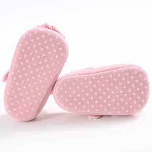Detalle de zapatos rosa para bebé con suela blanda, puntos antideslizantes y flor