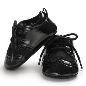 Detail of black patent leather baby brogue shoes with decorative perforations