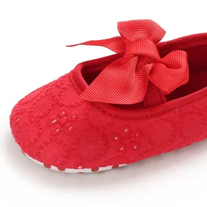 Vue détaillée d'une chaussure de princesse rouge pour bébé avec nœud et broderie