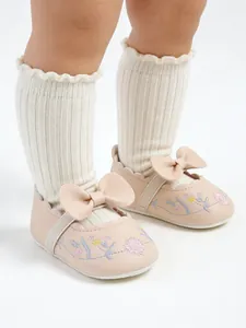 Close-up of pink baby princess shoes with floral embroidery and bow detail