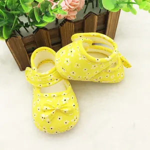 Detailed close-up of yellow baby walker shoes with white floral pattern and bow