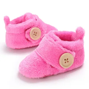 Detailed view of soft pink plush winter baby shoes featuring large wooden buttons.