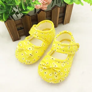 Yellow baby walking shoes with white floral pattern and decorative bow detail.