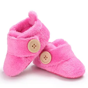 Cozy pink plush baby pre-walker shoes with soft soles and wooden button detail.