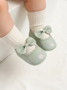 Close-up of pale green baby shoes with floral embroidery and a bow detail