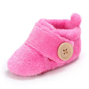 Close-up of pink plush baby bootie with decorative wooden button and soft texture.
