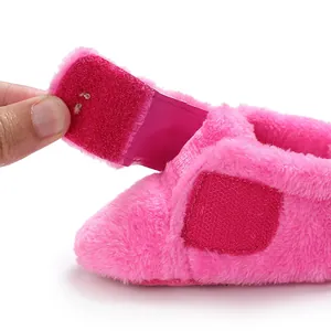 Close-up of pink fuzzy baby shoe showing the adjustable velcro fastener detail.