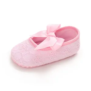 Gros plan sur une chaussure de marche rose pour bébé avec broderie florale et nœud