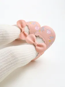 Detailed view of pink baby princess shoes featuring floral embroidery and cute bow detail