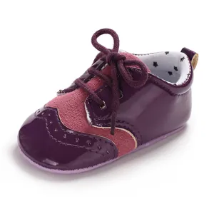 Detailed view of purple patent leather and suede infant shoes with lace-up bow