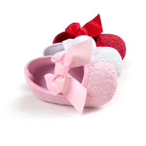 Close-up of embroidered baby princess shoes with large bows in pink, white, and red colors.