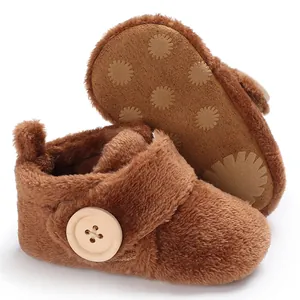 Soft brown fluffy winter baby booties with decorative wooden button and non-slip sole