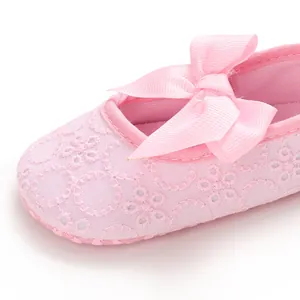 Vue détaillée de la chaussure de princesse rose pour bébé avec broderie et nœud.