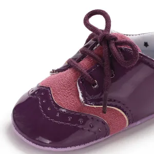 Macro detail of purple patent leather baby brogue shoes with pink suede accents