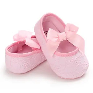 Détail de chaussures de princesse roses pour bébé avec broderie et nœud en ruban.