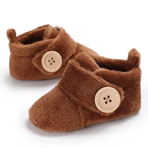Soft brown plush baby shoes with decorative wooden buttons and velcro strap closure