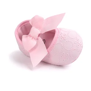 Detailed view of pink baby princess shoe with lace embroidery and large bow